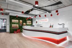 an office with white walls and red lights hanging from the ceiling, along with wooden floors