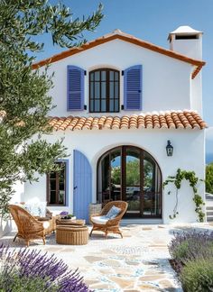 a white house with blue shutters and wicker furniture