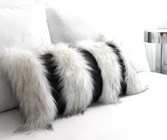 two white pillows with black and white fur on them sitting on a couch in a room