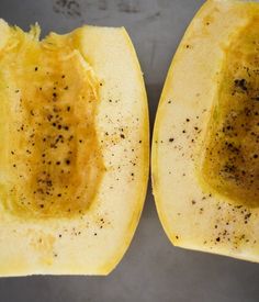 the inside of a squash with seeds and seasoning on it's side, cut in half