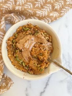 a white bowl filled with oatmeal and topped with peanut butter on top