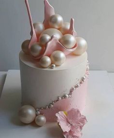 a white cake with pink decorations and pearls