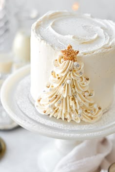 a white frosted cake decorated with a gold christmas tree decoration on top of it