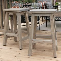 two wooden stools sitting next to each other on a wood floor in front of a table