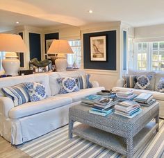 a living room with blue and white furniture in it's centerpiece, along with two lamps on either side of the couch