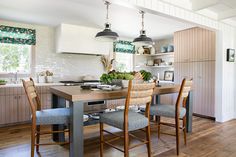 a kitchen table with four chairs around it and two hanging lights over the counter top