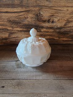 a small white bowl sitting on top of a wooden floor next to a wood wall