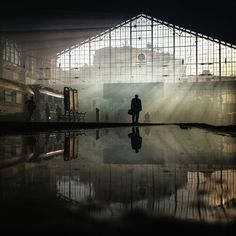 a man is standing in the middle of a building with its reflection on the water