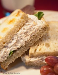 a close up of a sandwich on a plate with grapes