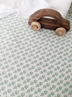 a wooden toy car sitting on top of a green and white tablecloth covered bed