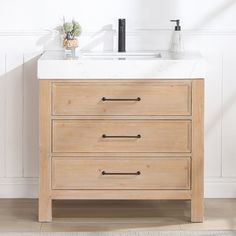 a bathroom vanity with two drawers and a white counter top in front of a wall mounted faucet