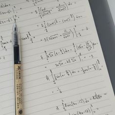 a pen sitting on top of a notebook with some calculations written in front of it