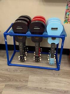 three ukulele guitars are sitting on a blue rack in front of a wall