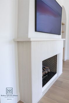 a flat screen tv mounted on the wall above a fireplace in a room with hardwood floors