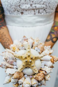 a bride holding a wedding bouquet made out of seashells and starfishes