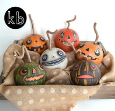 painted pumpkins with faces on them sitting in a sack