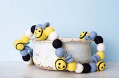 a yellow and black beaded bee necklace on a white pot with blue wall in the background