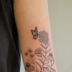 a woman's arm with a butterfly and flowers tattoo on the left side of her arm