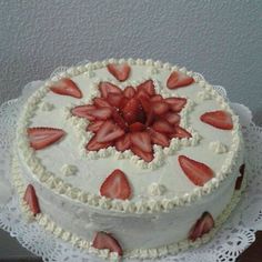 a white cake topped with sliced strawberries on top of a doily