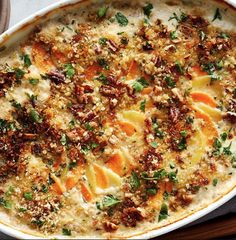 a casserole dish with carrots, parsley and pecans