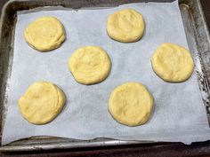 six uncooked doughnuts on a baking sheet