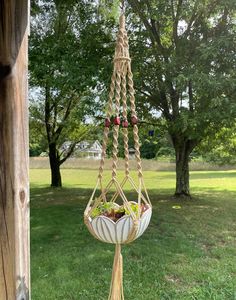 a hammock hanging from a wooden pole in the grass with flowers on it