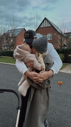 a man and woman kissing on the street with houses in the back ground behind them