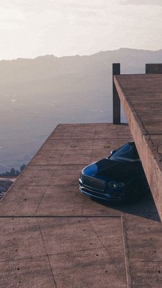 a blue car is parked on the side of a building with mountains in the background