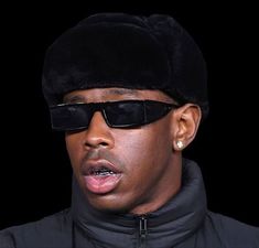 a man wearing sunglasses and a black hat is making a face with his tongue out