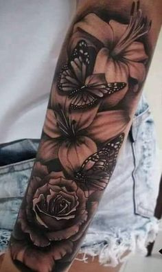 a black and white tattoo with flowers on the arm, butterflies flying over it in the background