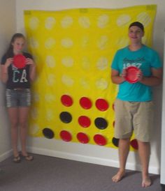 two people standing in front of a giant board with circles on it and one person holding a frisbee