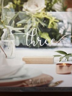 there is a sign that says three on the table next to some flowers and candles