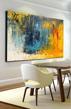 an abstract painting hangs on the wall above a dining room table with chairs and a rug