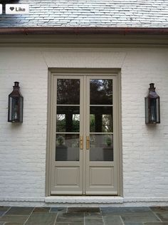 a white brick building with two doors and three lanterns on the side of each door