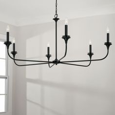 a black chandelier hanging from the ceiling in a room with white walls and windows