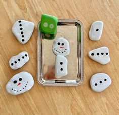 some white rocks with black dots on them and green dices in the shape of snowmen