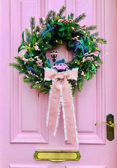 a pink door with a wreath on it that has a stuffed animal in the middle