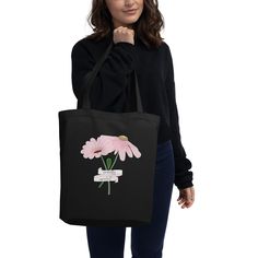 a woman holding a black shopping bag with pink flowers