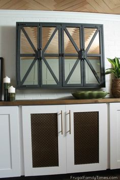 a kitchen with white cupboards and a large mirror on the wall above it's cabinet doors