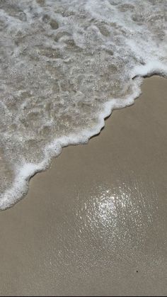 the water is foamy on the sand at the beach