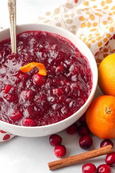 cranberry sauce in a white bowl surrounded by oranges and cinnamon sticks