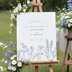 an easel with a sign and flowers on it