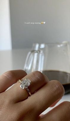 a person's hand holding a diamond ring