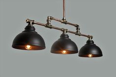 three lights are hanging from the ceiling in an industrial - style lighting fixture with metal fittings