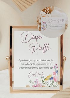 a sign that says diaper raffle with flowers on it and a tag hanging from the back