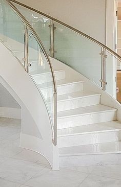 there is a white staircase with glass railings on the top and bottom handrail