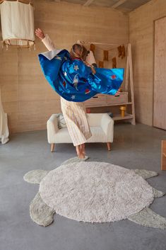 a woman in a room with a turtle rug on the floor and she is wearing a blue kimono over her shoulders