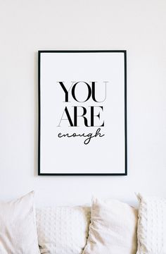 a black and white poster with the words you are enough on it above a couch