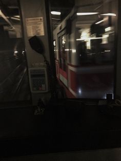 a red and white train traveling through a subway station at night with its lights on