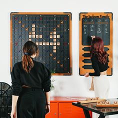 two women standing next to each other in front of a wall with numbers on it